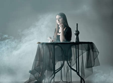 Woman sitting behind table in smokeの写真素材