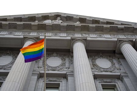 Lesbian, gay, bisexual, and transgender pride flag flying outside a government buildingの写真素材