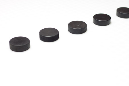 A series of hockey pucks with one in sharp focus