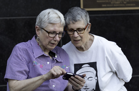 An older lesbian couple sharing the news via their phone after a judge struck down Wisconsin