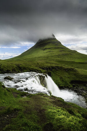 A beautiful waterfall and mountain in west Icelandの写真素材