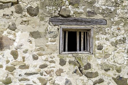 An old empty wooden window in a stone wallの写真素材
