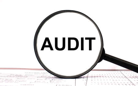 Magnifying glass with text AUDIT on financial tablesの写真素材