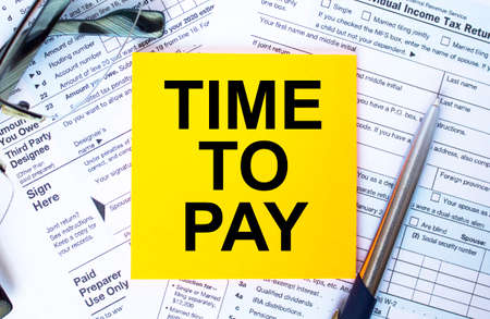 Tax-filling concept. Text Time To Pay on note paper with the U.S IRS 1040 form,pen and glassesの写真素材