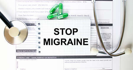 Text Stop Migraine in a notebook on medical forms with a phonendoscope and green pills. Medical conzeptの写真素材