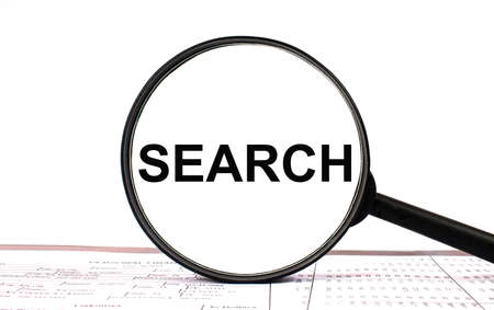 Magnifying glass with text SEARCH on financial tablesの写真素材