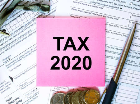 Financial concept. Text Tax 2020 on note paper with the US IRS 1040 form, pen and glassesの写真素材
