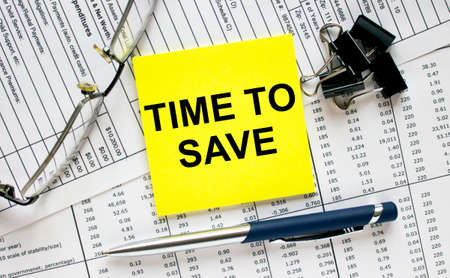 Text Time To Save on financial tables with pen, glasses and paper clips. Business and financial conzeptの写真素材