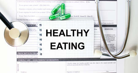 Text Healthy Eating in a notebook on medical forms with a phonendoscope and green pills. Medical conzeptの写真素材