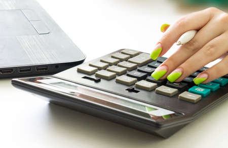 Financial data analyzing. Counting on calculator. Hand with clock on calculatorの写真素材