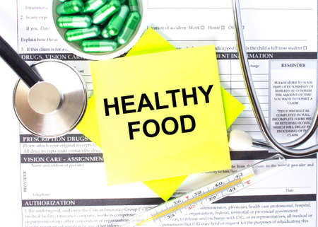 Text Healthy Food in a notebook on medical forms with a phonendoscope and green pills. Medical conzeptの写真素材