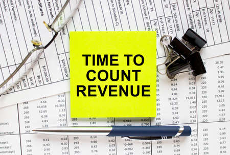 Text Time To Count Revenue on financial tables with pen, glasses and paper clips. Business and financial conzeptの写真素材