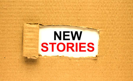 The text New Stories appearing behind torn brown paperの写真素材