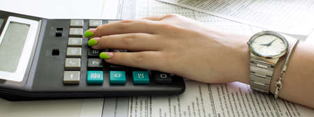 Financial data analyzing. Counting on calculator. Hand with clock on calculatorの写真素材