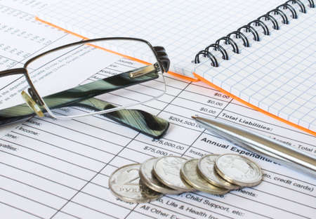 Pen on financial and accounting reports with coins stacks, glasses and calculator in background. Concepts of tax planning and budget management.の写真素材