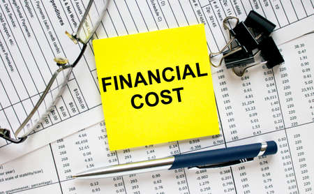 Text Financial Cost on financial tables with pen, glasses and paper clips. Business and financial conzeptの写真素材