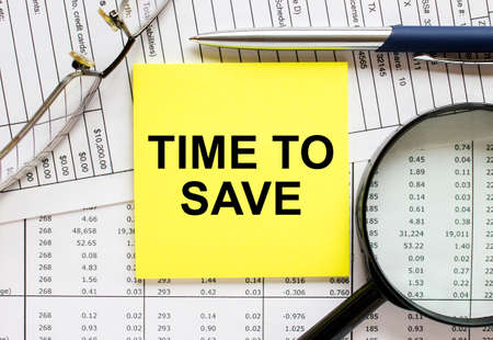 Text Time To Save on financial tables with pen, glasses and magnifying glass. Business and financial conzeptの写真素材
