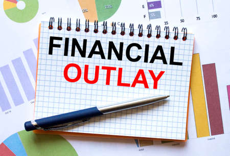 Notepad with text Financial Outlay on business charts and pen. Business and financial conzeptの写真素材