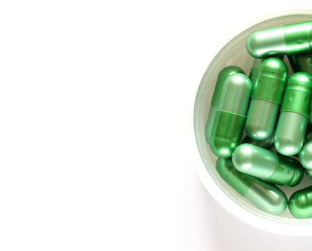 A pile of green pills on a white backgroundの写真素材