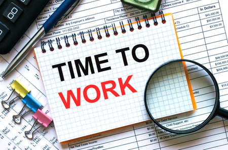 Text Time To Work on notepad with calculator, clips, pen on financial reportの写真素材