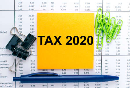 Text Tax 2020 on financial tables with pen, glasses and paper clips. Business and financial conzeptの写真素材