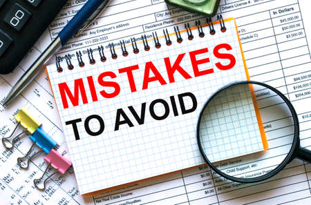 Text Mistakes To Avoid on notepad with calculator, clips, pen on financial reportの写真素材