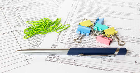 A blue metal pen sits on the financial tables with multi-colored stationery clips. Business and...