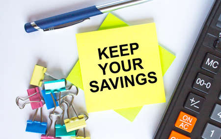 Text Keep Your Savings on yellow stickers with calculator, blue pen and paper clips. Business and financial conceptの写真素材
