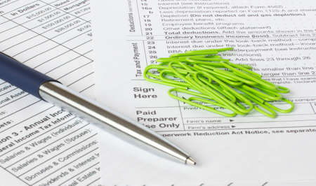 A blue metal pen sits on the financial tables with green paper clips. Business and financial conceptの写真素材
