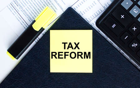 Yellow sticker with text Tax Reform laying on the folder with yellow marker and calculator. Business conceptの写真素材