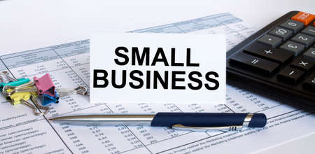 Text Small Business on white card with blue metal pen, calculator and paper clips on financial table. Business and financial conceptの写真素材