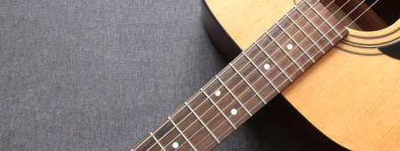 Part of a blue acoustic guitar on a gray wooden background