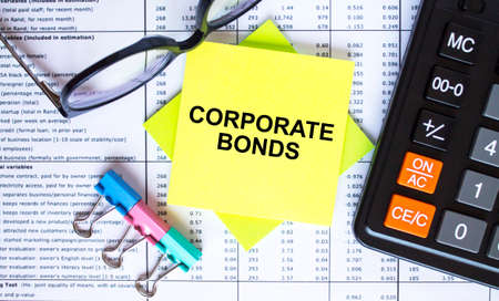 Text Corporate Bonds on yellow stickers with calculator, eyeglasses and paper clips. Business and financial conceptの写真素材