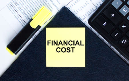Yellow sticker with text Financial Cost laying on the folder with yellow marker and calculator. Business conceptの写真素材