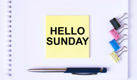 Yellow sticker with text Hello Momday lying on a white Notepad with a pen and paper clips. Concept pgotoの写真素材