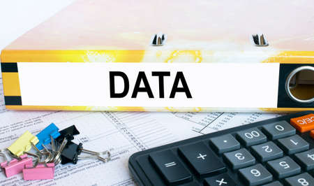 Text Data on the folder that is located on the financial reports with calculator and stationery clips. Business and financial conceptの写真素材