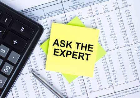 Sticker with text Ask The Expert lying on the financial tables. Calculator with metal pen. Business and financial conceptの写真素材