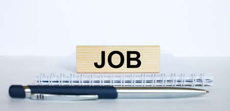 The word Job on a bar of wood, lying on a Notepad with a metal blue pen. Business concept photoの写真素材
