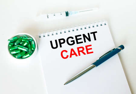 Text Upgent Care written in a notebook with a blue pen and a bunch of pills. Can be used as a medical conceptの写真素材