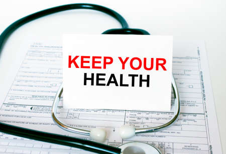 Text Keep Your Health on the white card with the stethoscope and medical documents. Medical concept photoの写真素材