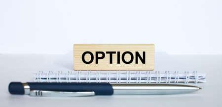 The word Option on a bar of wood, lying on a Notepad with a metal blue pen. Business concept photoの写真素材
