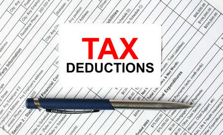 Text Tax Deductions written on a business card lying on financial tables with a blue metal pen. Business and financial conceptの写真素材