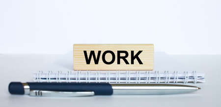 The word Work on a bar of jenga wood, lying on a Notepad with a metal blue pen. Business concept photoの写真素材