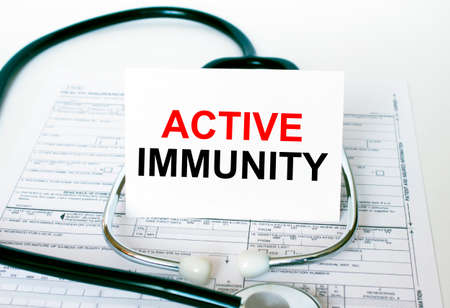 Text Active Immunity on the white card with the stethoscope and medical documents. Medical concept photoの写真素材