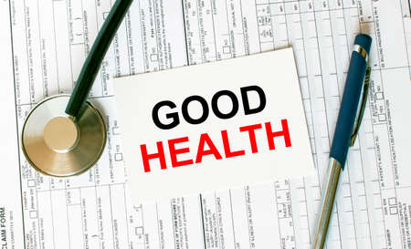 Text Good Health on the white card with the stethoscope, pen and medical documents. Medical concept photoの写真素材