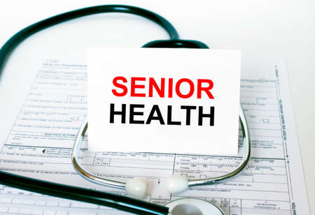 Text Senior Health on the white card with the stethoscope and medical documents. Medical concept photoの写真素材