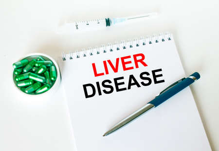 Text Liver Disease written in a notebook with a blue pen and a bunch of pills. Can be used as a medical conceptの写真素材