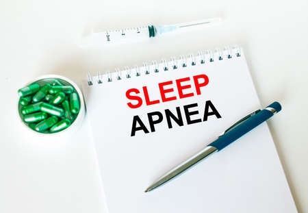 Text Sleep Apnea written in a notebook with a blue pen and a bunch of pills. Can be used as a medical conceptの写真素材