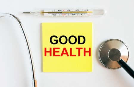 Yellow sticker with the text Good Health. A thermometer with a phonendoscope on a white background. Can be used as a medical concept photoの写真素材