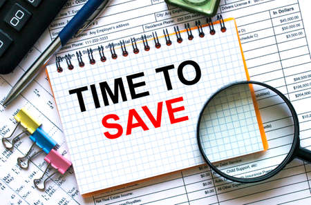 Text Time To Save on notepad with calculator, clips, pen on financial report. Financial and business concept photoの写真素材